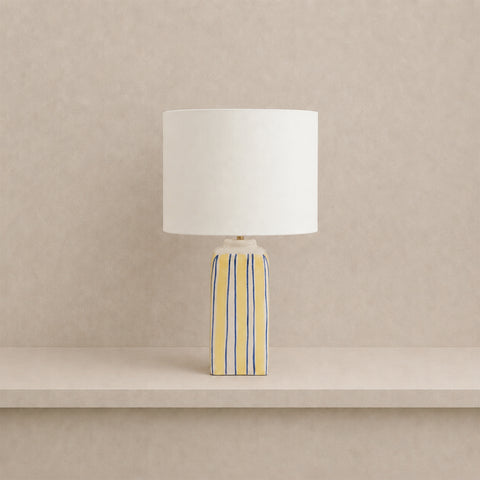 Ceramic table lamp with yellow and blue vertical stripes and a white drum shade.