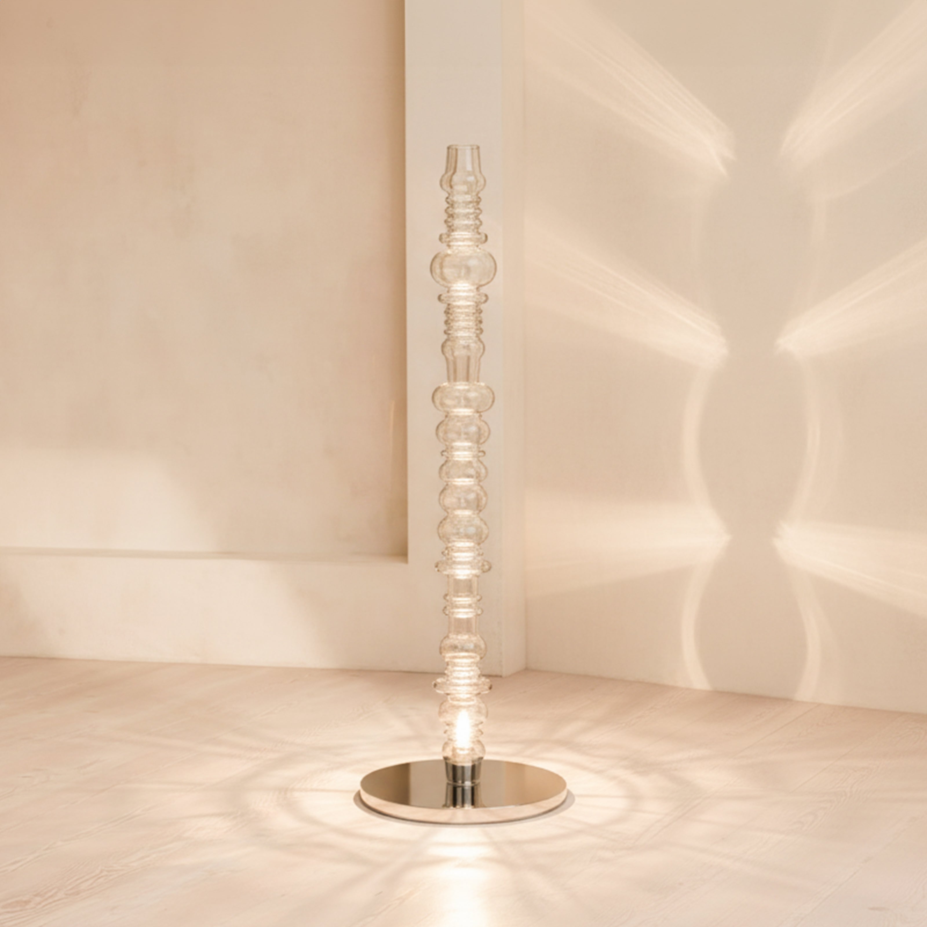 Reef glass floor lamp placed in corner with warm light pattern on wall, modern interior lighting.