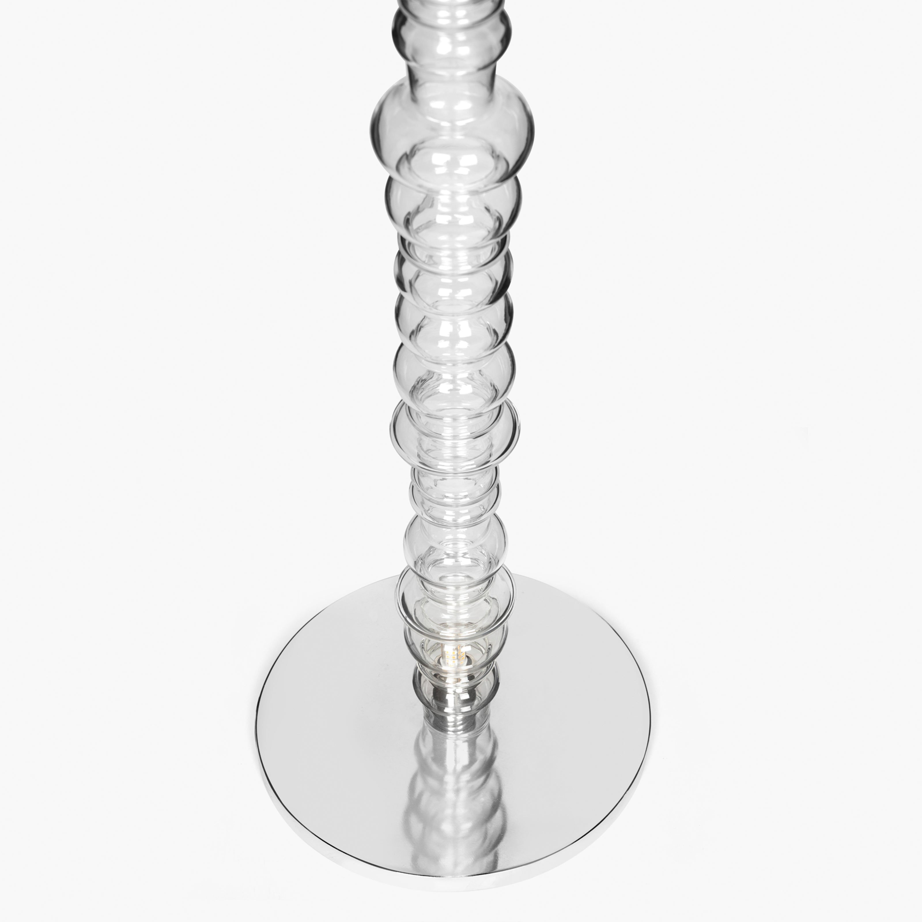 Reef floor lamp base detail with circular metal base and transparent glass stem.