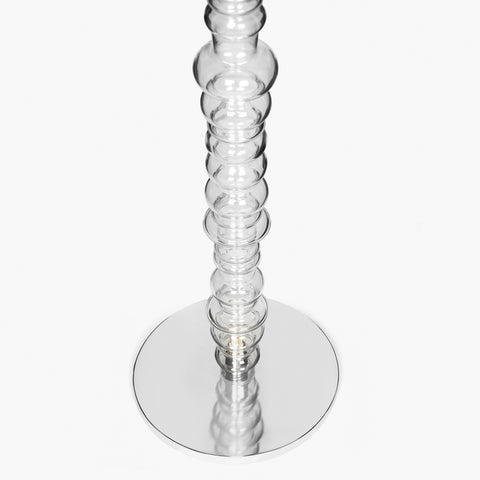 Reef floor lamp base detail with circular metal base and transparent glass stem.