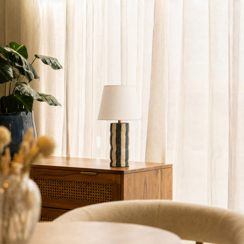Table lamp displayed in a bright room with a wooden cabinet and light curtains.