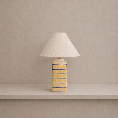 Ceramic table lamp with yellow and blue stripes and a white shade.