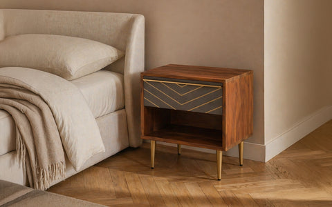 Modern wooden bedside table with drawer and open shelf beside upholstered bed.