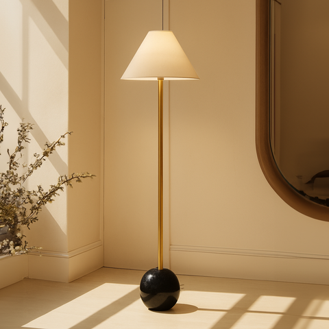 A modern floor lamp with a gold stem and white conical shade styled in a cozy reading nook, perfect as floor lamps for living room or bedroom lamps.