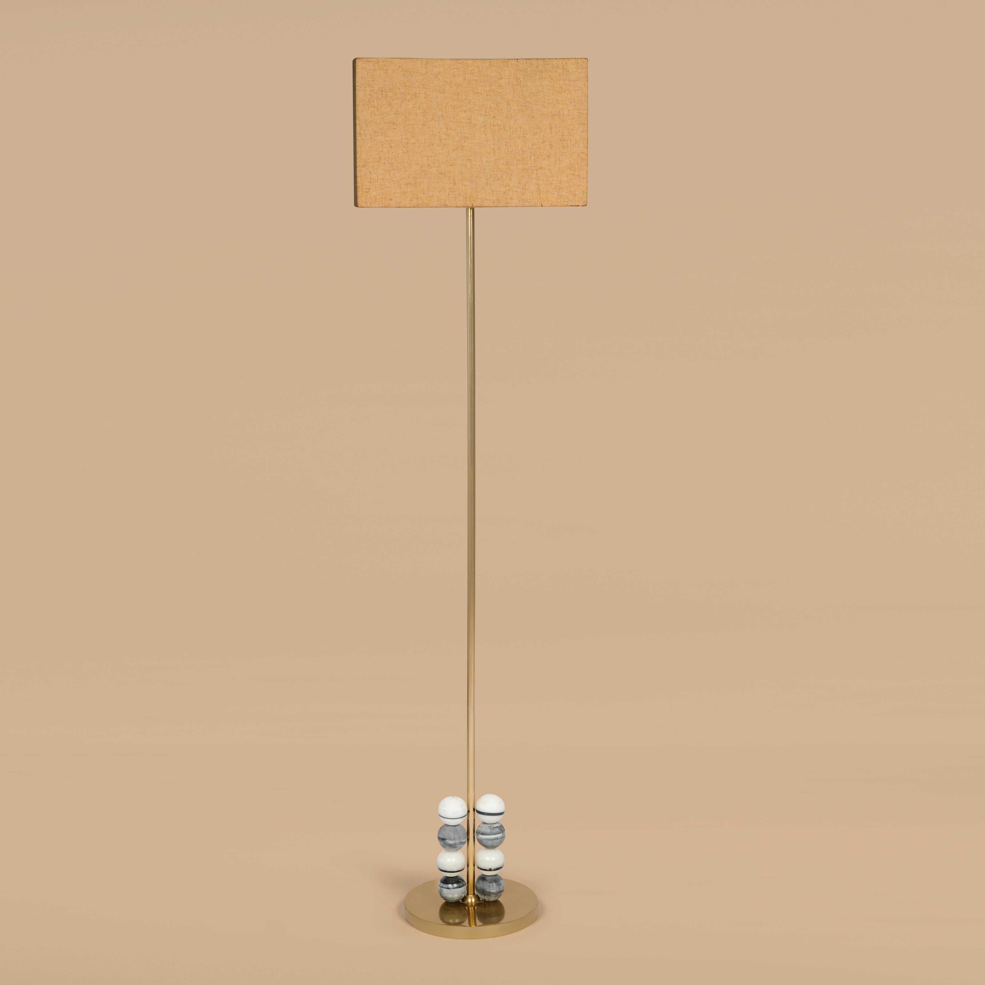 Contemporary floor lamp with fabric shade and brass stem in neutral interior setting.