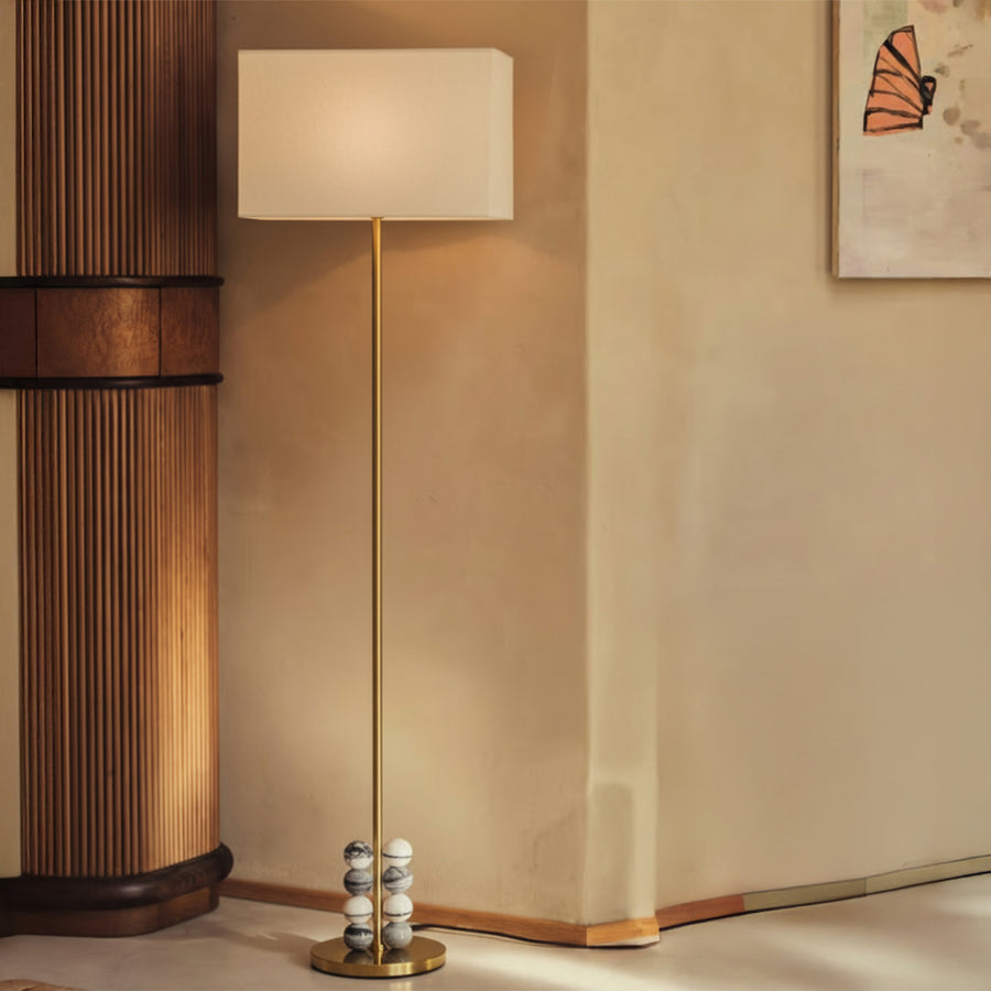 Brass floor lamp with linen shade and marble bead base styled in a warm modern living room.