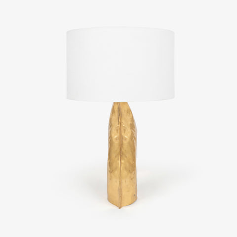 Side profile of a gold bedside lamps structure with a single glowing globe.