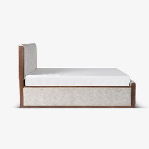 Side view of beige upholstered bed with wood base