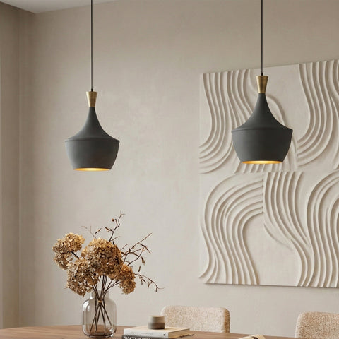 Two modern black pendant lights above a dining table with textured wall art.