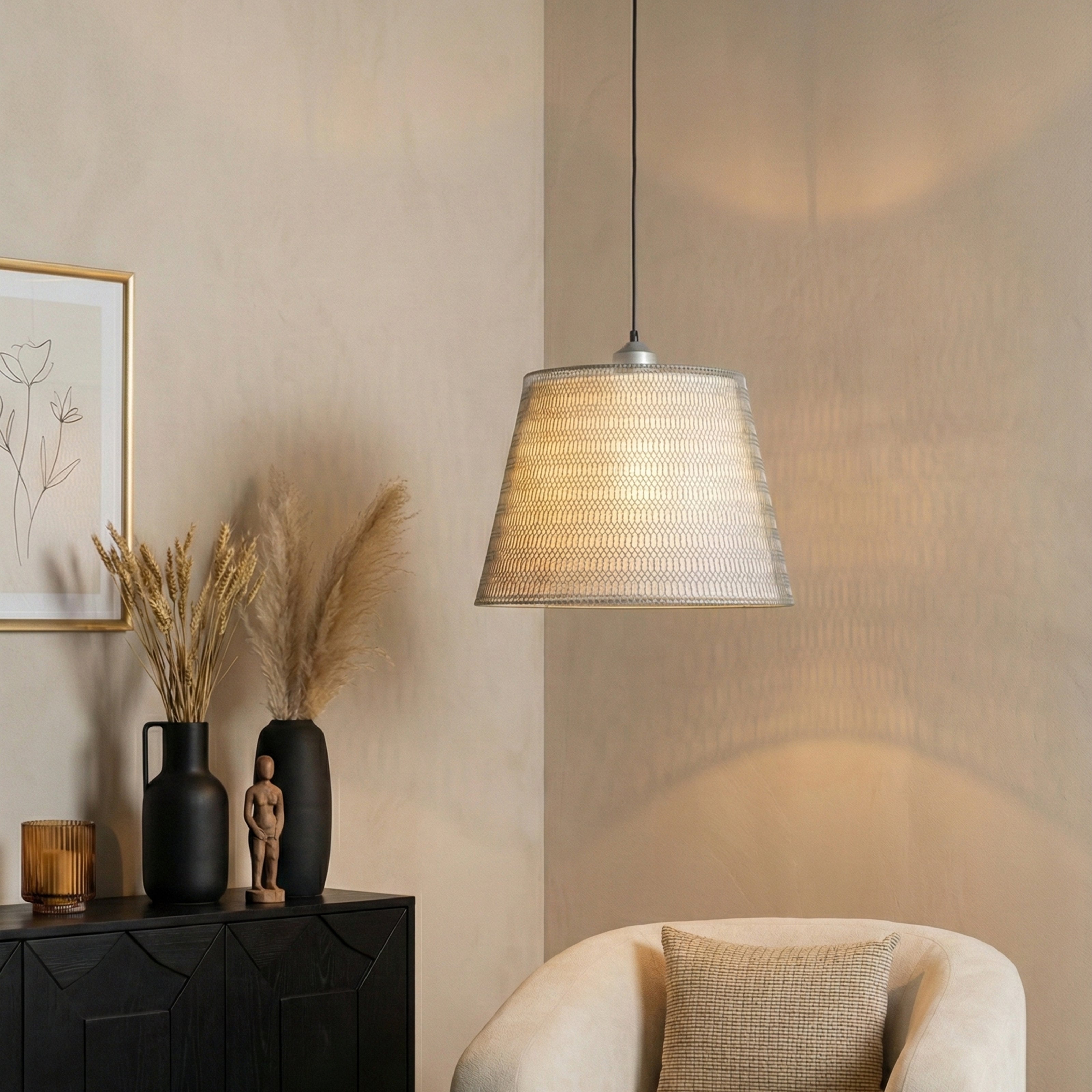 Fabric drum pendant light above a cozy armchair in a neutral living space.