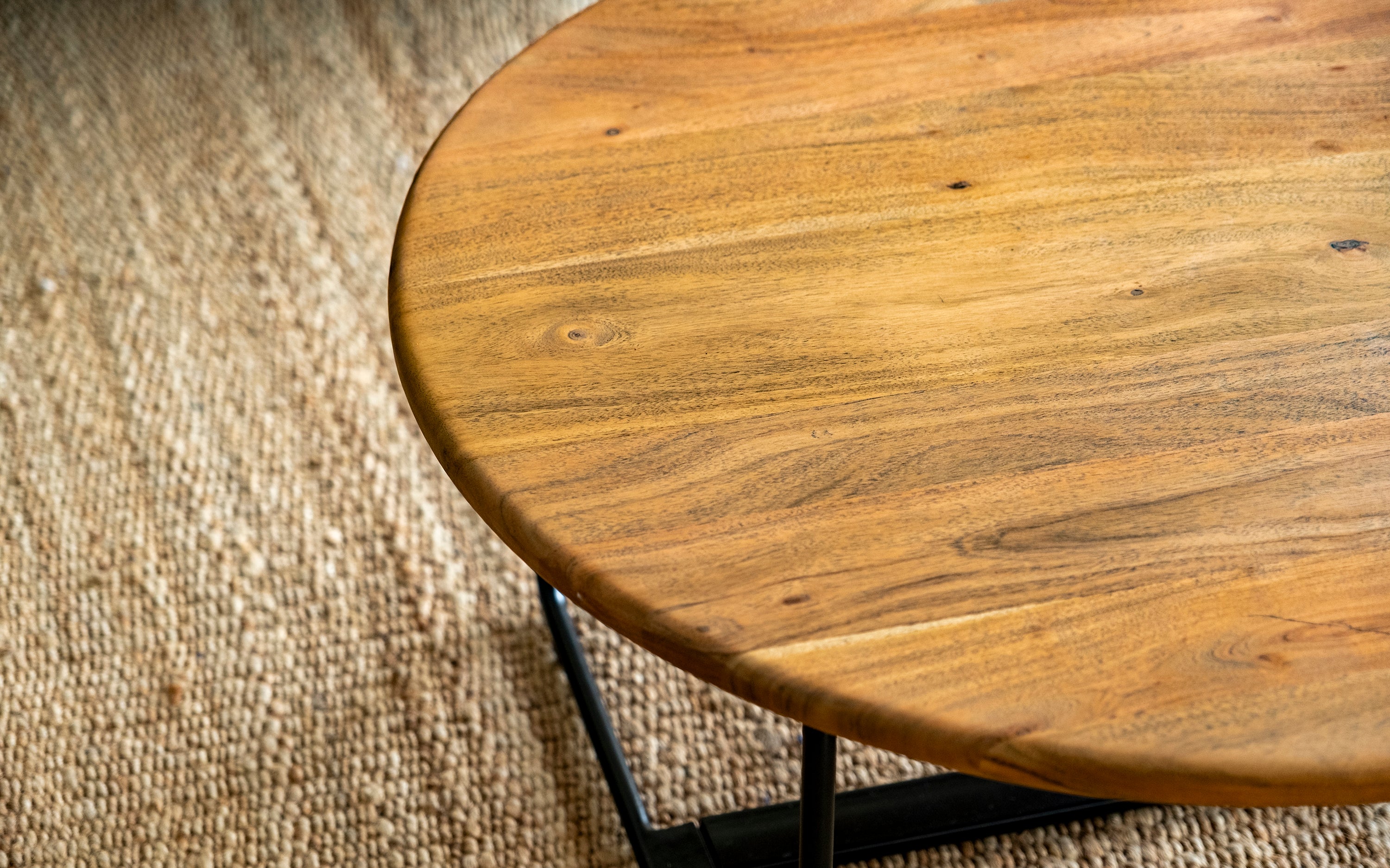 Jasper Round Coffee Table: Acacia Wood with Black Metal Base - Close shot - from left angle - Orange Tree