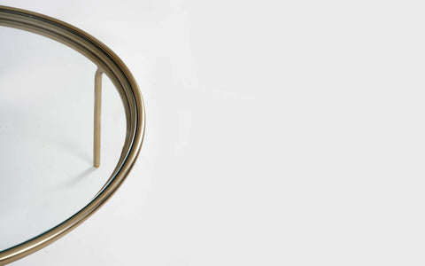 Olivia Glass Top Coffee Table with a brass finish on a mild steel frame. Sleek, modern coffee table is perfect for contemporary living rooms.