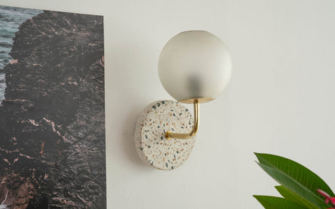 Eros White Wall Lamp with Terrazzo base, Gold-finished Mild Steel, and Frosted Glass shade.  This lamp is available online in India.